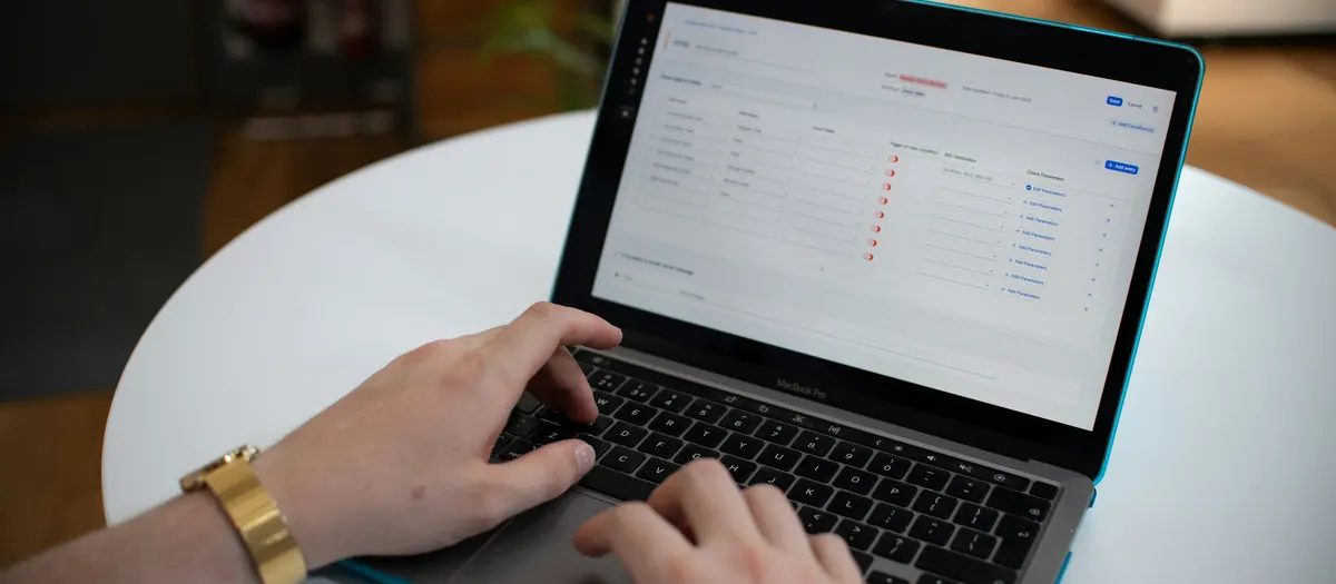 Hands typing on a laptop showing a spreadsheet
